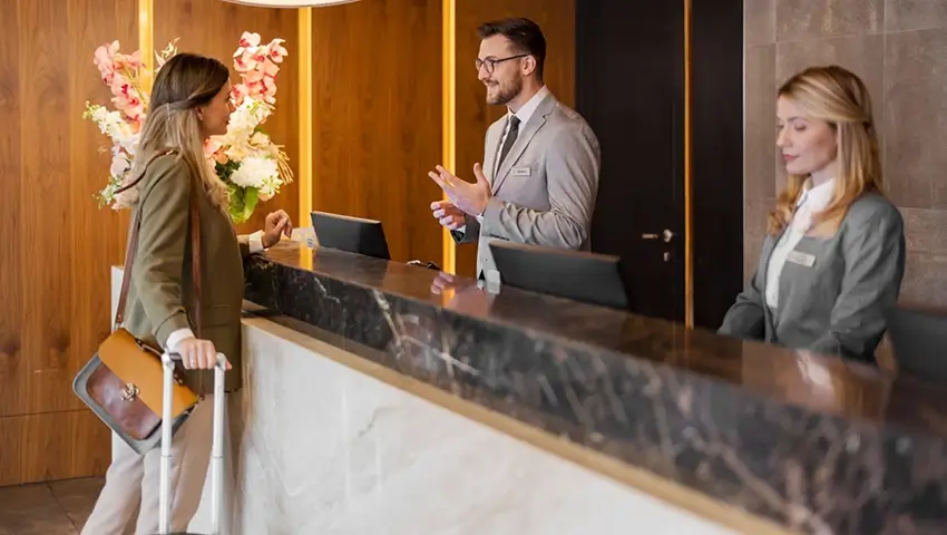 Male hotel receptionist assisting female guest